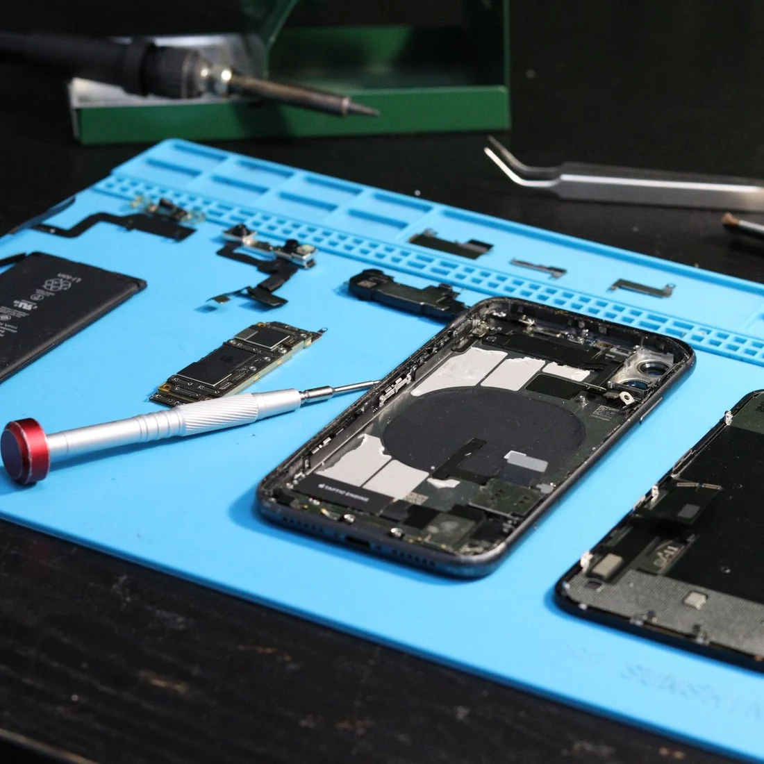 Celular desmontado sobre bancada de reparo com ferramentas
